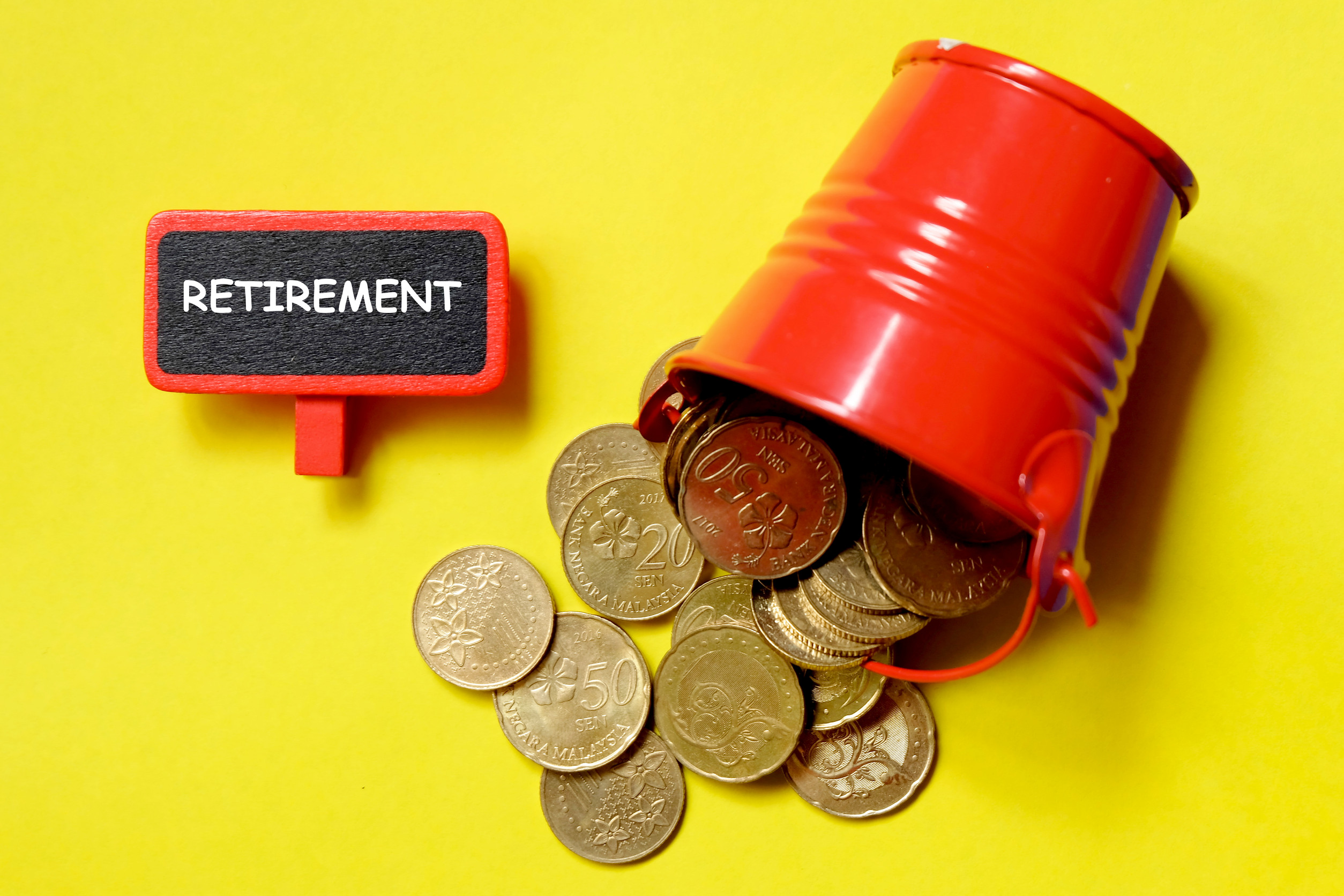 Buket spilling coins with a small board showing retirement wrtten on it to depict income solutions with retirement plans